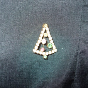 May include: A gold-tone Christmas tree brooch with clear, pink, and green rhinestones.