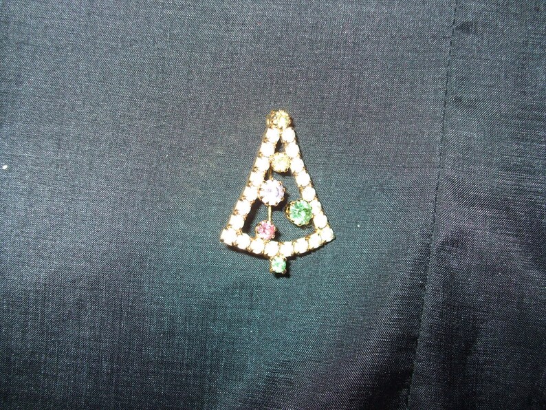 May include: A gold-tone Christmas tree brooch with clear, pink, and green rhinestones.