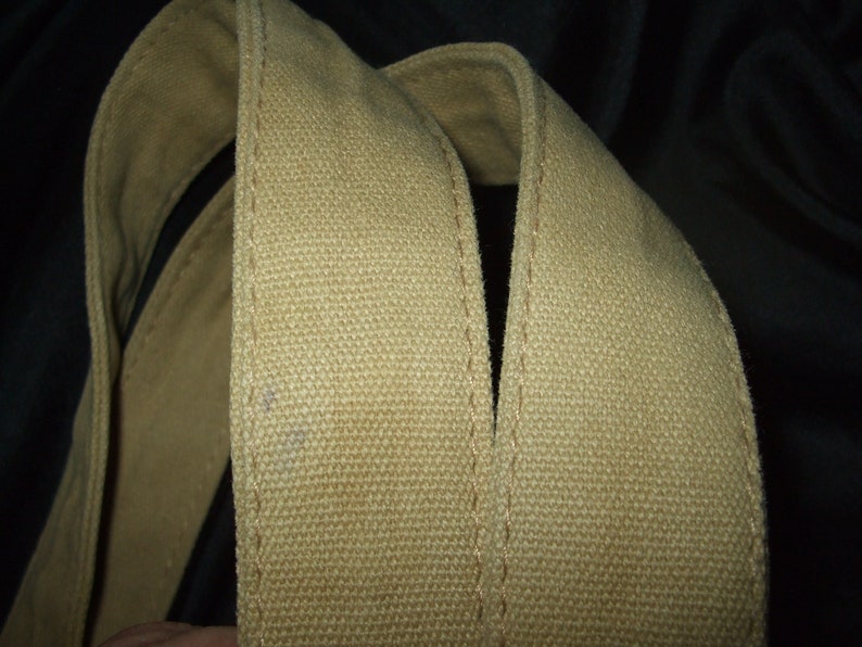 May include: Close-up of two beige canvas straps sewn together. The straps are thick and have a woven texture.