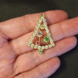 May include: A gold-tone Christmas tree brooch with clear, pink, green, and yellow rhinestones.