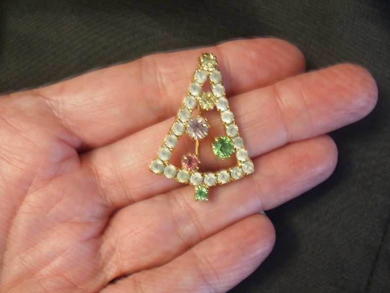 May include: A gold-tone Christmas tree brooch with clear, pink, green, and yellow rhinestones.