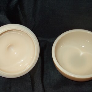 May include: Two empty, round, cream-colored ceramic bowls. The bowls are smooth and have a glossy finish.