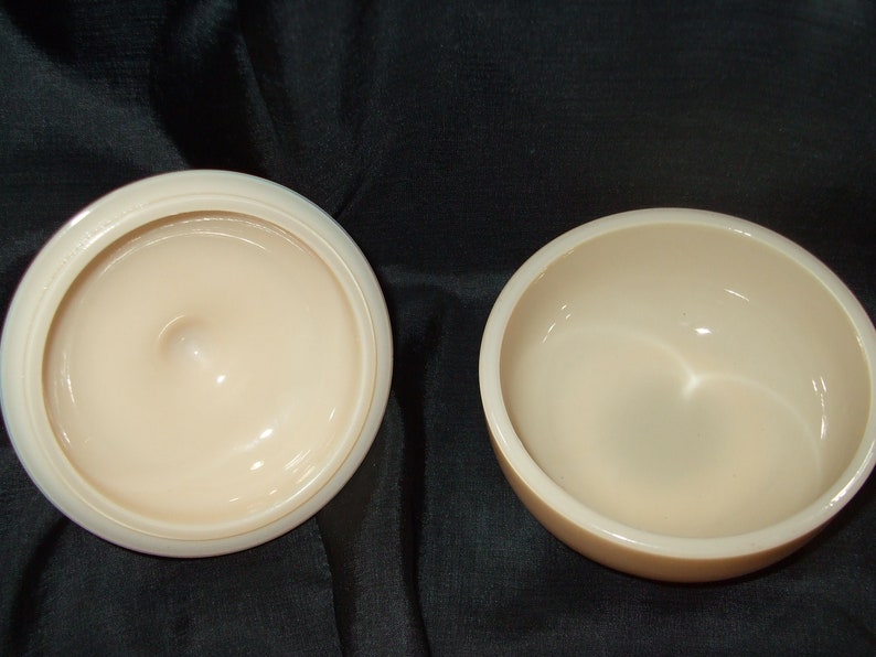 May include: Two empty, round, cream-colored ceramic bowls. The bowls are smooth and have a glossy finish.