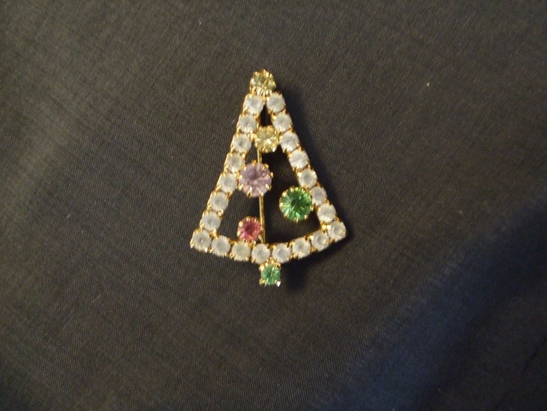May include: A gold-tone Christmas tree brooch with clear, green, and purple rhinestones.