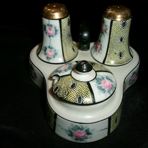 May include: A vintage ceramic salt and pepper shaker set with a matching condiment dish. The set features a yellow and black polka dot pattern with pink roses and green leaves.