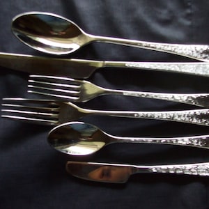 May include: A set of five silver-plated utensils, including a spoon, a butter knife, and three forks. The utensils have a textured, hammered finish.