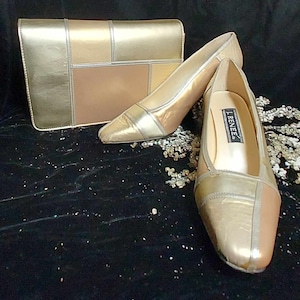 May include: A pair of gold and brown heeled shoes with a matching clutch. The shoes are made of leather and have a square toe. The clutch has a geometric design.