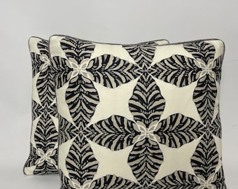 May include: Two decorative throw pillows with a black and white geometric pattern. The pattern features a repeating design of stylized leaves and flowers.