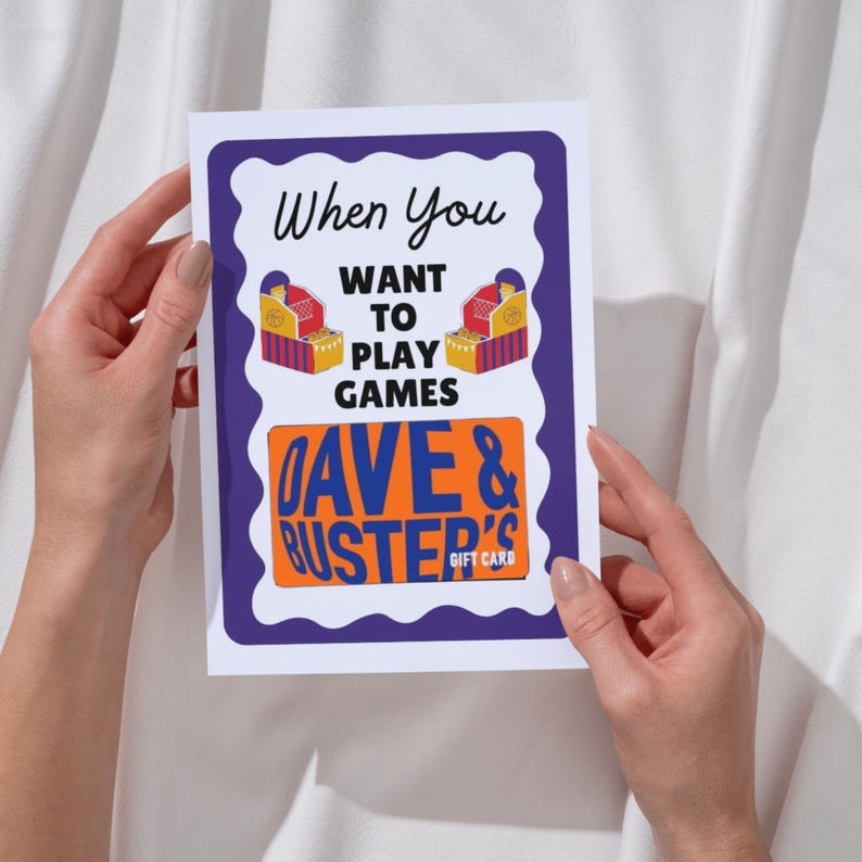 May include: A white card with a purple border and the text "When You Want To Play Games." The card features illustrations of arcade game machines and the "Dave & Buster's Gift Card" logo in orange.