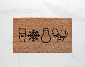 May include: A rectangular brown coir doormat with black line art of a coffee cup with a heart, snowflake, snowman, and mittens. The mat is designed for winter or holiday use.