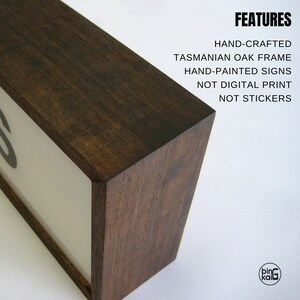 Pode incluir: Uma placa de madeira com uma moldura de carvalho da Tasm&acirc;nia castanho escuro. A placa &eacute; pintada &agrave; m&atilde;o e apresenta o texto "FEATURES" em mai&uacute;sculas. O texto abaixo de "FEATURES" diz "HAND-CRAFTED", "TASMANIAN OAK FRAME", "HAND-PAINTED SIGNS", "NOT DIGITAL PRINT" e "NOT STICKERS".