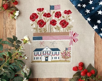 May include: Cross-stitch pattern featuring a red, white, and blue house with fireworks, a potted plant with red poppies, and a ribbon with a bow. The pattern is surrounded by a border of stars.