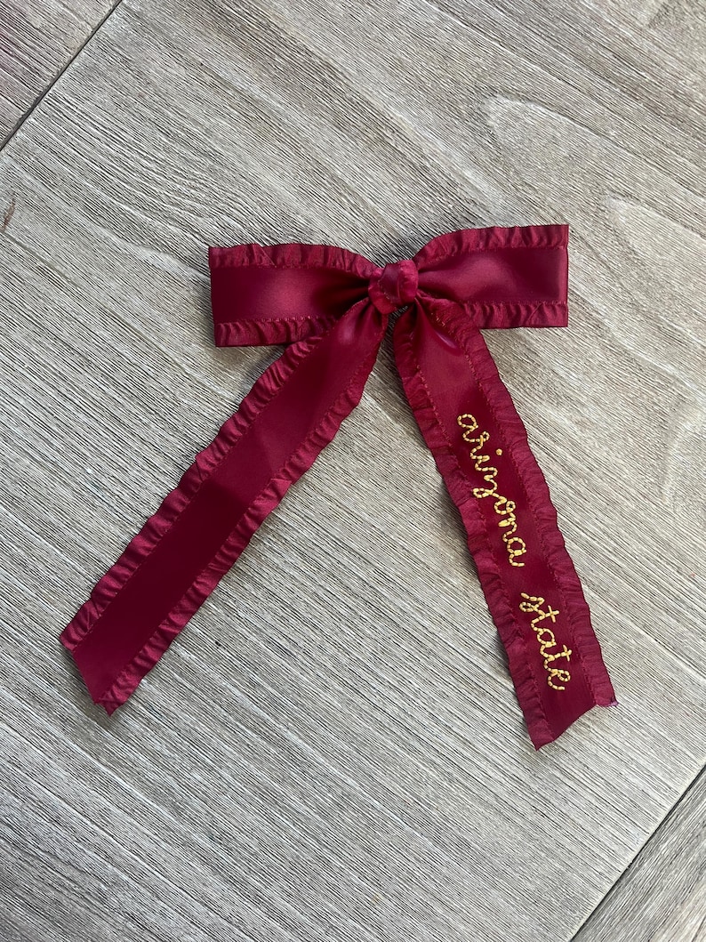 May include: A burgundy satin ribbon bow with a gold embroidered inscription that reads "original state".