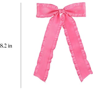 May include: A pink satin bow with ruffled edges. The bow measures 8.2 inches in length and 5.5 inches in width.