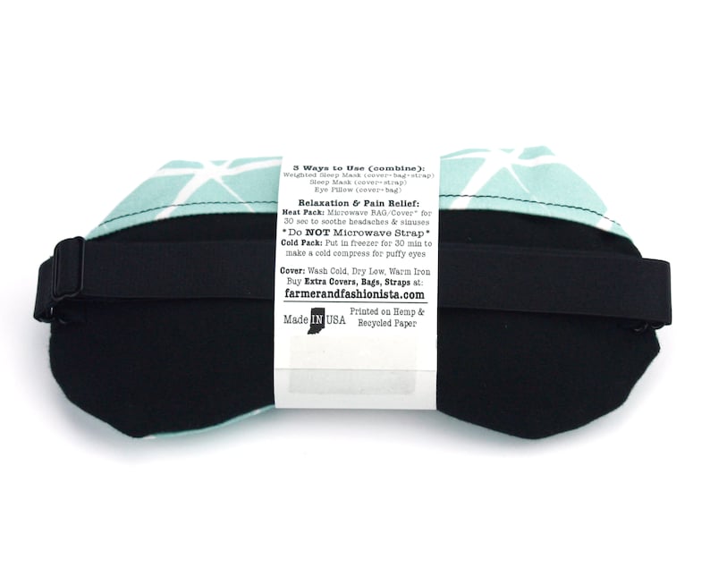 May include: A turquoise and white geometric patterned eye mask with a black adjustable strap. The back of the mask has a white label with instructions for using the mask as a hot or cold compress. The label reads "3 Ways to Use (combine): Welted Mask (cover-bag-strap) Sleep Mask (cover) Eye Pillow (cover-bag) Relaxation & Pain Relief: Heat Pack: Microwave BAG/Cover for 30 sec to soothe headaches & sinuses *Do NOT Microwave Strap Cold Pack: Put in freezer for 30 min to make a cold compress for puffy eyes Cover: Wash Cold, Dry Low, Warm Iron Buy Extra Covers, Bags, Straps at: farmerandfashionista.com Printed on Hemp & Made IN USA Recycled Paper"