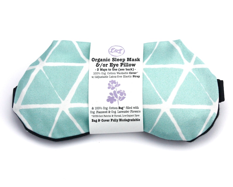 May include: A light blue sleep mask with a white geometric pattern. The mask is made of organic cotton and filled with flaxseed and lavender. The text on the label reads "Organic Sleep Mask &/or Eye Pillow - 3 Ways to Use (see back) - 100% Org. Cotton Washable Cover w/Adjustable Latex free Elastic Strap & 100% Org. Cotton Bag" filled with Org. Flaxseed & Org. Lavender Flowers 005-Cert Fabrics & Thread, Low Impact Dyes Bag & Cover Fully Biodegradable"