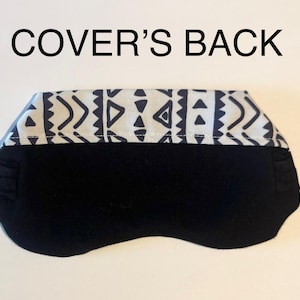 May include: Black sleep mask with a patterned top band. The top band features a white background with a repeating geometric design in navy blue. The text "COVER'S BACK" is above the mask.