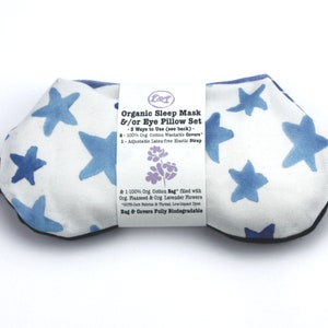 Puede incluir: Una m&aacute;scara para ojos blanca con un patr&oacute;n de estrellas azules y un borde negro. La m&aacute;scara est&aacute; hecha de algod&oacute;n org&aacute;nico y rellena de semillas de lino y lavanda. La etiqueta dice "Organic Sleep Mask &/or Eye Pillow Set - 3 Ways to Use (see back) - 100% Org. Cotton Washable Covers 1-Adjustable Latex free Elastic Strap & 1-100% Org. Cotton Bag" filled with Org. Flaxseed & Org Lavender Flowers 0016 Cert Paris & Thread, Low Impact Dyes Bag & Covers Fully Biodegradable"