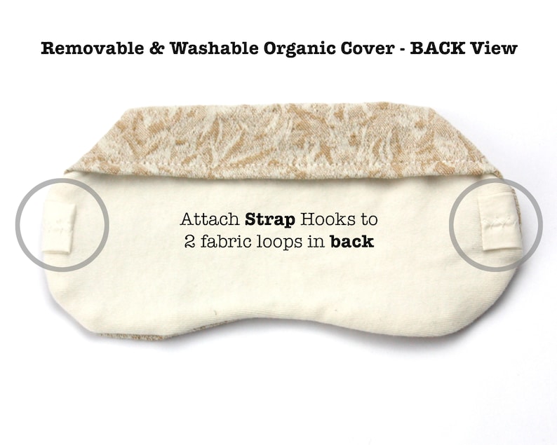 May include: Back view of a white eye mask with a removable and washable organic cover. The cover has a beige floral pattern. The eye mask has two fabric loops on the back for attaching strap hooks.