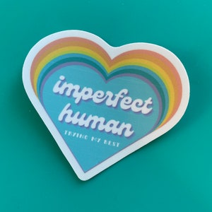 May include: A blue heart-shaped sticker with a rainbow border. The sticker says "imperfect human trying my best" in a retro font.