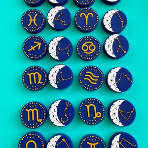 May include: Set of 16 blue and gold zodiac constellation charms with a crescent moon design. Each charm features a different zodiac symbol and constellation.