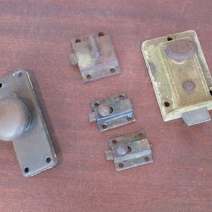 May include: Five antique door latches and knobs in various styles and finishes. The latches are made of metal and have a variety of finishes, including brass, bronze, and black. The knobs are also made of metal and have a variety of finishes, including brass and bronze.