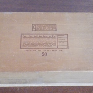 May include: A wooden box with a brown label that reads "Fact. No. 160 1st Dist. of Pa. FACTORY NO. 160 1ST DIST. PA. 50". The label also includes a table with the headings "PACKER", "HANDER", and "COLOR".