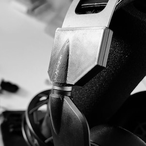 May include: Close-up of a black and silver headset with a microphone. The headset has a padded headband and earcups.