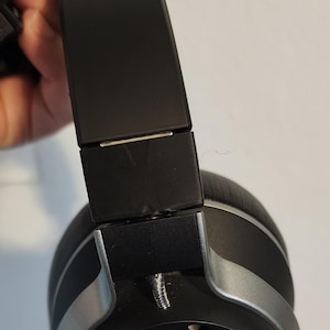 May include: Black headphones with silver accents. The headphones have a black headband with a silver band around the earcups.