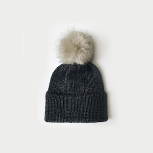 May include: A black knit beanie with a fluffy white pom pom on top.