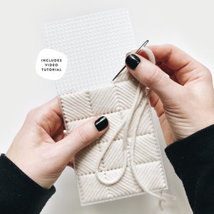 May include: A close-up of a person's hands working on a white yarn project on a plastic grid. The yarn is woven in a herringbone pattern. The image includes the text "Includes Video Tutorial".