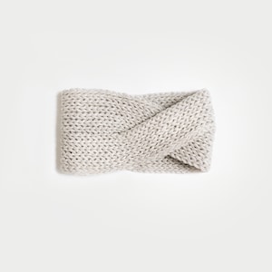 May include: A light grey knitted headband with a twisted design.
