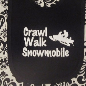 May include: Black bib with white text that reads "Crawl Walk Snowmobile" and a white silhouette of a snowmobile.