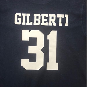 May include: A navy blue t-shirt with white lettering that reads "GILBERTI 31".