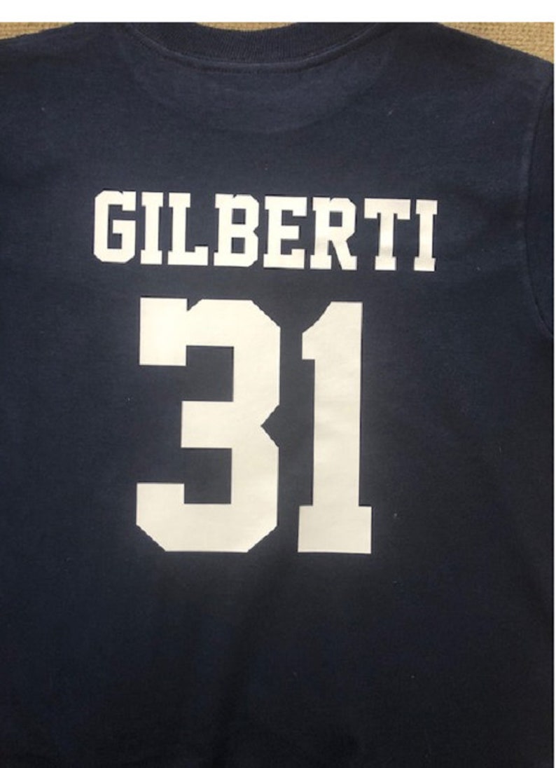 May include: A navy blue t-shirt with white lettering that reads "GILBERTI 31".
