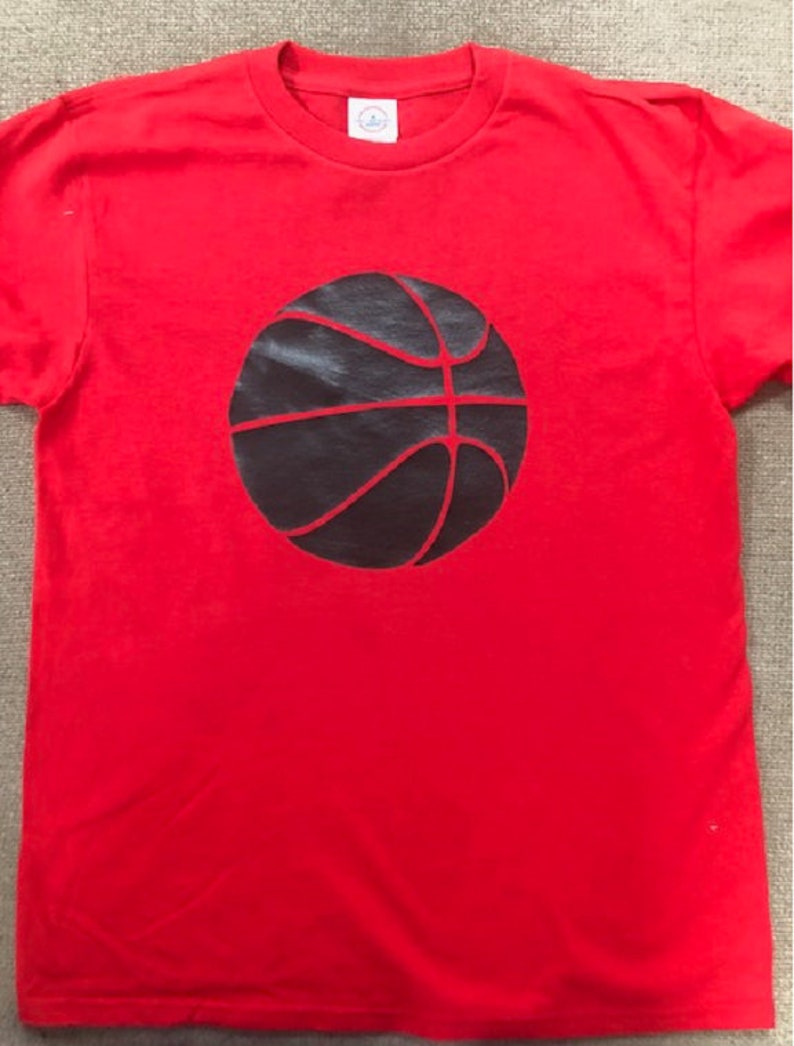 May include: Red t-shirt with a black basketball graphic.