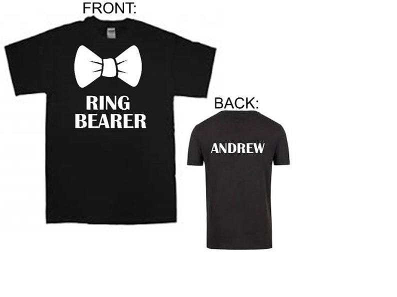 Puede incluir: Camiseta negra con texto blanco que dice "Ring Bearer" y una pajarita. La parte posterior de la camiseta tiene texto blanco que dice "Andrew".