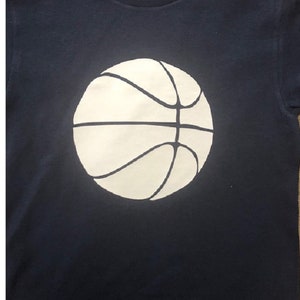 May include: A navy blue t-shirt with a white basketball graphic.