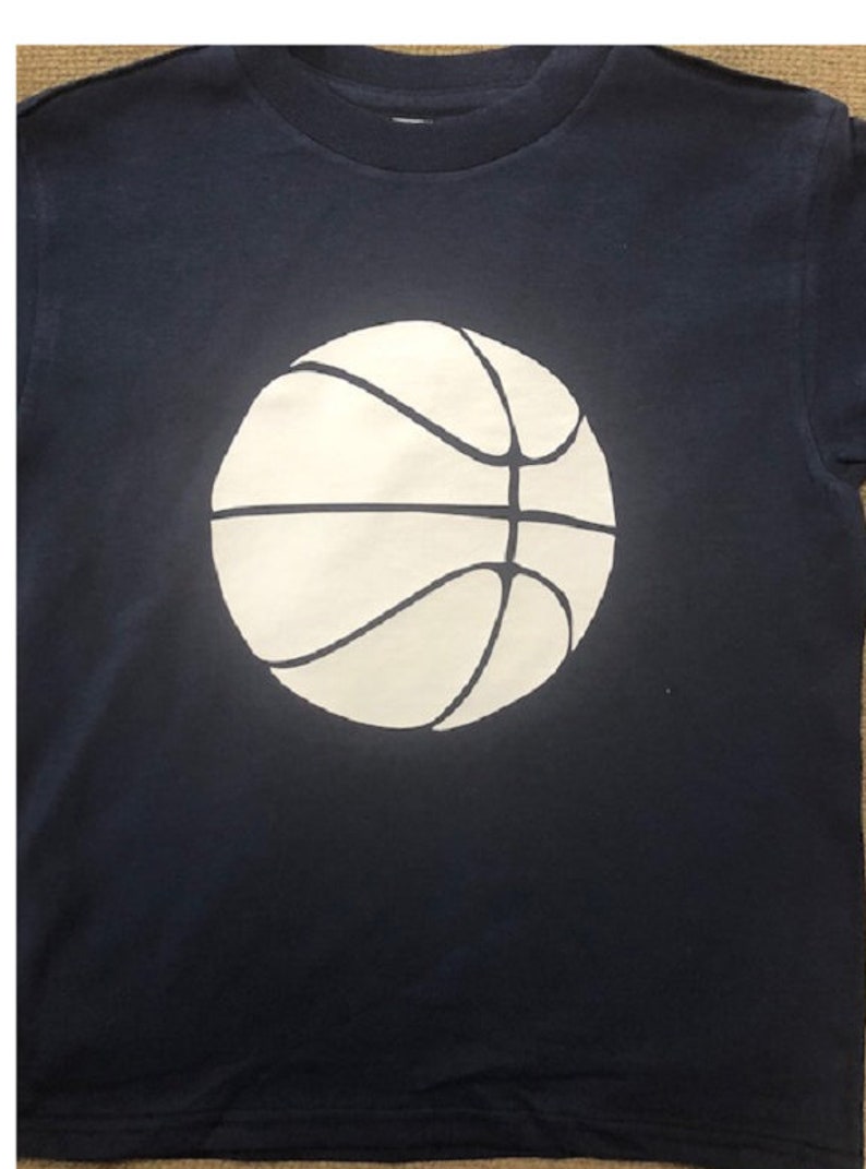 May include: A navy blue t-shirt with a white basketball graphic.