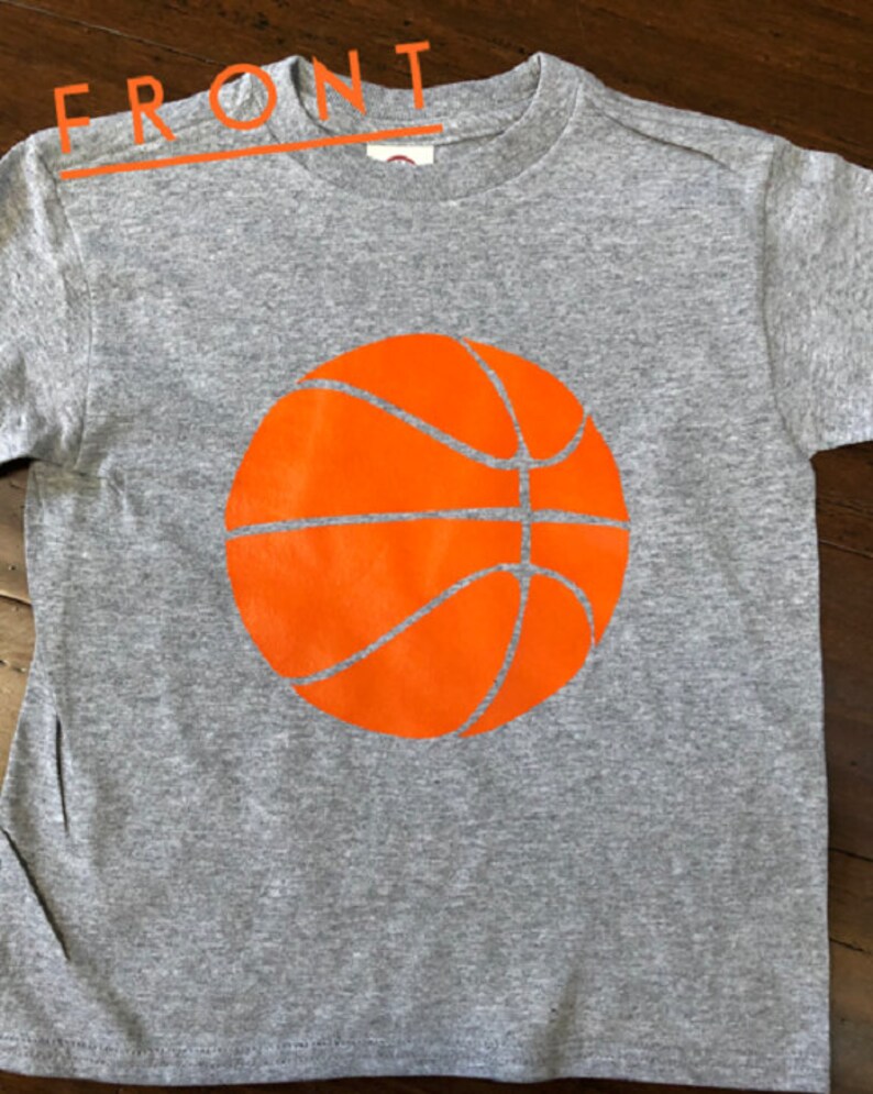 May include: A gray t-shirt with an orange basketball graphic on the front.