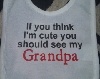 May include: White baby bib with black text that reads "If you think I'm cute you should see my Grandpa" with the word "Grandpa" in red.