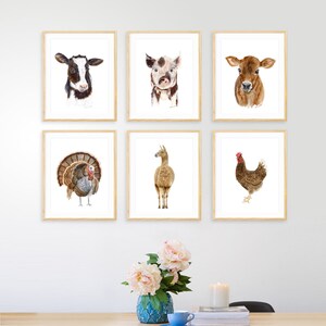 May include: Six framed watercolor paintings of farm animals, including a cow, pig, calf, turkey, llama, and chicken. The paintings are all in a white frame with a light wood finish.