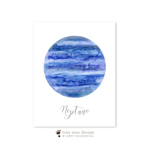 以下が含まれることがあります： 青と紫の色合いで描かれた海王星の水彩画。惑星は白い背景に囲まれ、海王星という単語が惑星の下に筆記体で書かれている。画像の下部には黒い文字で「tiny toes design by Brett Blumenthal」と書かれている。
