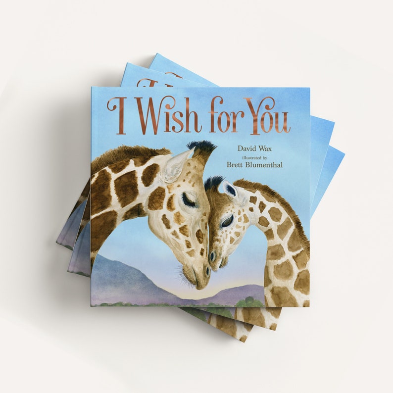May include: A stack of children's books with a blue cover and the title "I Wish for You" in gold lettering. The cover features a watercolor illustration of two giraffes nuzzling each other.