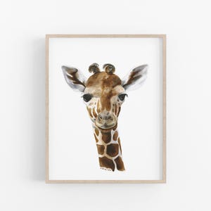 A framed print of a giraffe's head, with its distinctive brown and white spotted pattern and large eyes, is displayed on a white wall.