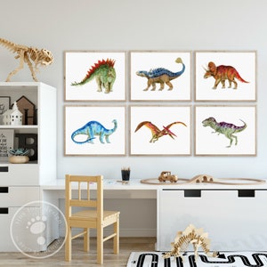 Pode incluir: Seis impress&otilde;es de dinossauros em aquarela emolduradas em um quarto infantil. As impress&otilde;es apresentam uma variedade de dinossauros, incluindo um estegossauro, um tricer&aacute;topo, um pterod&aacute;ctilo e um tiranossauro rex. As impress&otilde;es est&atilde;o penduradas em uma parede branca acima de uma mesa e uma cadeira brancas.