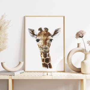 a framed painting of a giraffe's face, displayed on a wooden shelf with a vase and a book.