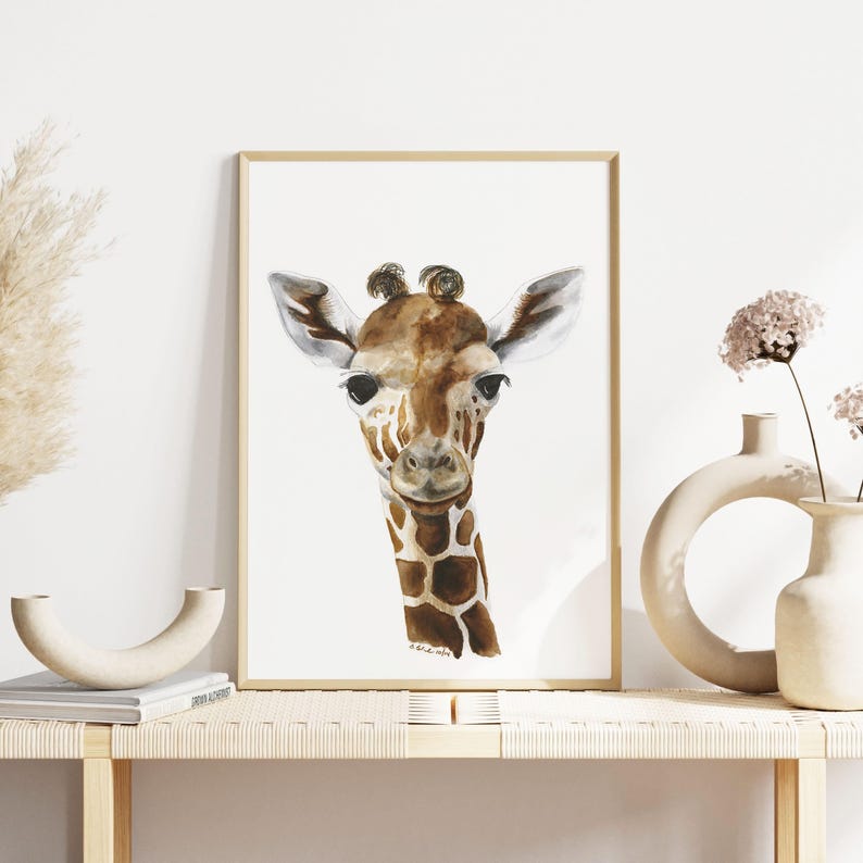 a framed painting of a giraffe's face, displayed on a wooden shelf with a vase and a book.