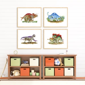 May include: Four framed watercolor paintings of dinosaurs on a white wall. The paintings are arranged in a grid pattern. The dinosaurs are depicted in various poses and colors. The paintings are surrounded by a white wall and a wooden shelf with toys and books.