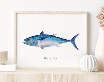 May include: Watercolor print of a Bluefin Tuna fish in shades of blue, with a yellow fin. The artwork is displayed in a light wood frame. The text "Bluefin Tuna" is below the fish.